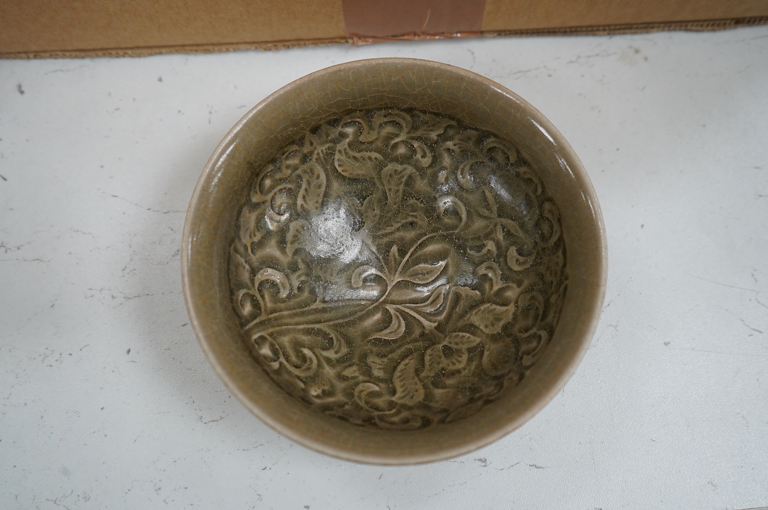 A Chinese cased carved celadon glazed bowl, 11.5cm diameter. Condition - good